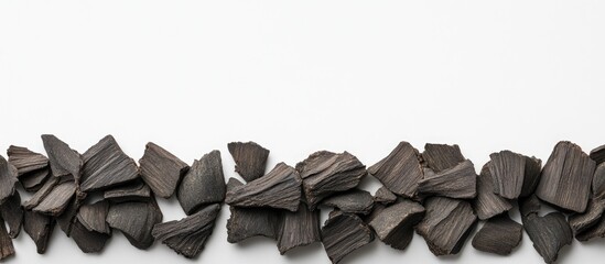 Poster - Black decorative stone chips arranged in a line on a white background with Copy Space for text placement.