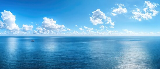 aerial view of bright blue ocean horizon with a solitary yacht on calm waters under white clouds and
