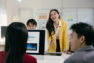 Poster - Diverse team of asian professionals are actively collaborating in a modern office setting, analyzing data displayed on a computer screen, with a businesswoman leading the discussion