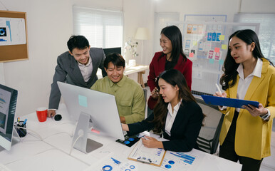 Poster - Group of young asian businesspeople working together, analyzing financial data on a computer screen during a productive meeting in a modern office, demonstrating teamwork and collaboration