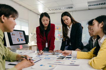 Poster - Group of young asian businesspeople analyzing charts and reports during a productive meeting in a modern office, working together to achieve company goals and improve performance
