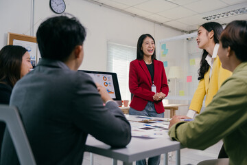 Fototapete - Asian businesswoman leading a meeting, sharing a presentation with her team in the office, discussing marketing strategies and data analysis, fostering collaboration and teamwork