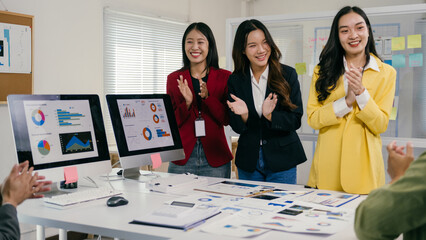 Fototapete - Asian businesswomen are clapping hands with their colleagues after successful presentation of project strategy in the office, celebrating their success