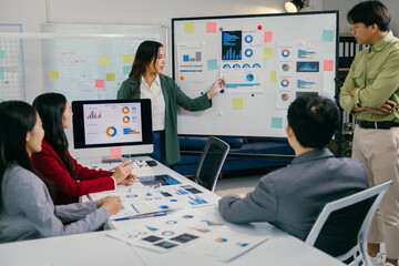 Sticker - Businesswoman presenting marketing strategy on a whiteboard, showcasing charts and statistics while engaging with a team of colleagues during a collaborative office meeting