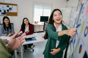 Poster - Happy asian businesswoman explaining marketing data on a whiteboard, engaging colleagues during a productive meeting in a modern office, fostering teamwork and collaboration