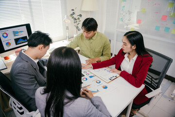 Aufkleber - Four asian businesspeople are sitting around a table, collaborating on analyzing financial charts and graphs, developing growth strategies during a productive office meeting