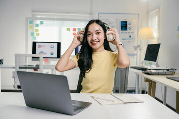 Poster - Young beautiful asian businesswoman wearing headphones is relaxing listening to music and using laptop computer working at home office