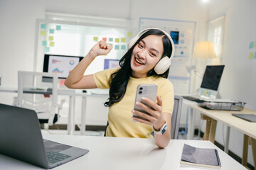 Poster - Young business woman is enjoying listening to music working in office, relaxing and dancing in her chair during break at work