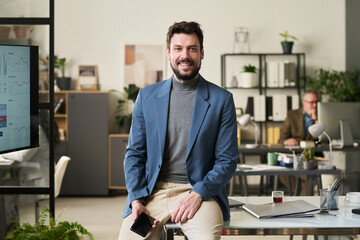 Poster - Young successful director of business company with mobile phone looking at camera while sitting on his workplace in office