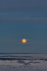 Wall Mural - The full moon above the mist of Lake Mjøsa and the cultural landscape of Toten, Norway, in January.