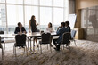 © fizkes - Attractive businesslady, trainer or business coach make speech during corporate briefing event gathered with diverse teammates in conference room to share ideas, solutions, explain her business vision