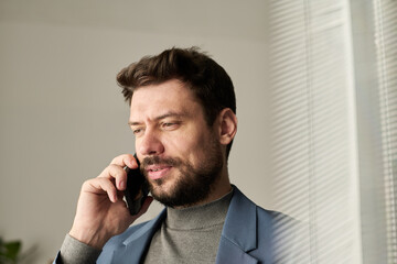Poster - Confident manager with smartphone by ear speaking to colleague while organizing work in front of camera in office