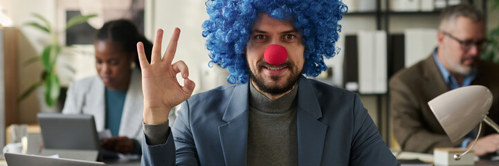 Poster - Header of young smiling male white collar worker in formalwear, clown wig and nose looking at camera and showing okay gesture