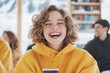 © Tondone - A joyful young girl in a yellow hoodie smiling while looking at her smartphone