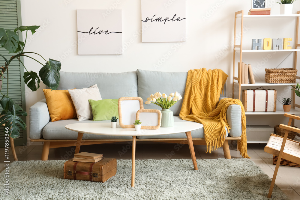 Interior of stylish living room with sofa, posters and blank frames on table