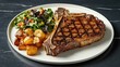 © วรรณภา มะโนศรี - A juicy T-bone steak with a side of roasted potatoes and fresh salad, beautifully arranged on a round white plate, ready to be enjoyed