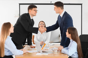 Wall Mural - Business men shaking hands after negotiations in conference hall