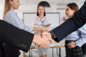 Wall Mural - Business men shaking hands after negotiations in conference hall, closeup