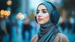 © Evgenii - Young Muslim woman wearing a grey hijab and modern headphones, standing confidently in an urban environment with blurred lights in the background, concept of technology and lifestyle, copyspace