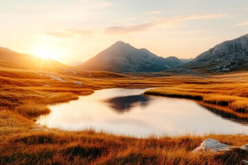 Wall Mural - Golden sunset reflecting on tranquil lake surrounded by mountains and grassy fields during evening hours