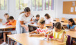 © JackF - Positive boys and girls studying and woman teacher helping in classroom