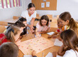 © JackF - Young female teacher and happy schoolkids playing interesting learning board game during lesson in classroom