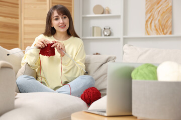 Wall Mural - Beautiful woman learning to knit with online course at home