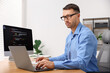 © New Africa - Programmer working on laptop and computer at wooden desk indoors