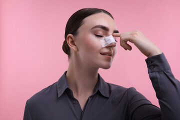 Wall Mural - Woman with medical bandage on her nose after plastic surgery operation against pink background