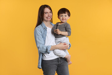 Canvas Print - Happy mother with her cute little son on yellow background