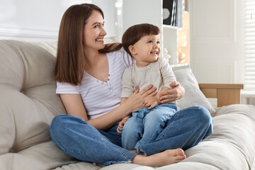 Wall Mural - Happy mother with her cute little son on sofa at home