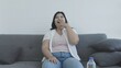 © anut21ng Stock - Chubby Asian woman watching TV on the sofa at home