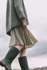 Wall Mural - woman wearing rubber boots, walking outdoors, cloudy sky on background