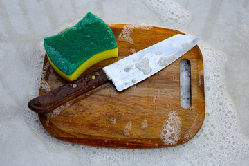 Wooden cutting board in foam of dishwashing liquid.