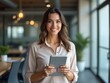 © NETI studio - Portrait of young Hispanic professional business woman standing in office. Happy female company executive, smiling businesswoman entrepreneur corporate leader manager looking at camera using tablet