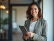 © NETI studio - Portrait of young Hispanic professional business woman standing in office. Happy female company executive, smiling businesswoman entrepreneur corporate leader manager looking at camera using tablet