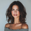 © shabbir - A High-Detail Portrait of a Woman with Voluminous Brunette Waves, Subtle Makeup, and a Relaxed Gray Blouse.