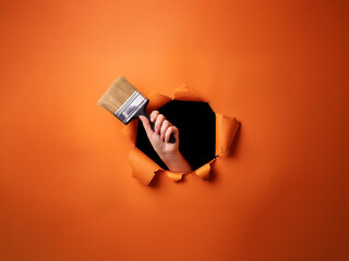 Aufkleber - A hand holding a paintbrush emerges from a hole in a vibrant orange background.  The scene is minimalist and suggestive of creativity and new beginnings.