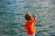 © Volodymyr - Child boy on lake throw a stone in water. Sea landscape background.