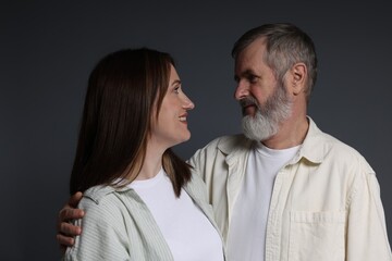 Wall Mural - Happy daughter and her father looking at each other on dark background