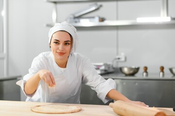 Beautiful female chef cooks cheese pizza in restaurant kitchen. The concept of semi-finished products and frozen food