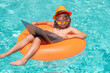 © Volodymyr - Funny little businessman freelancer relaxing in the pool, using laptop computer in summer water. Child online working on tropical sea.
