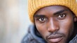© Kultivad - Close Up Portrait of Thoughtful Young Black Man in Yellow Beanie Reflecting Modern Economic Challenges with Warm Tones and Neutral Background
