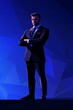 © grey - A businessman in a suit stands with his arms crossed, in a low-poly style, against a blue background with a dark color palette.