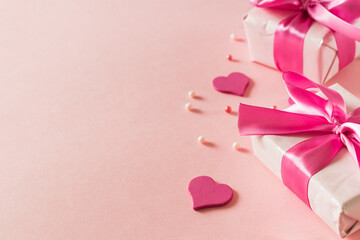 Wall Mural - Pink hearts and gift box with ribbon on a light pink background