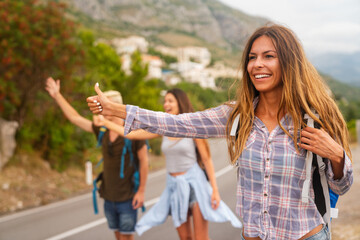 Wall Mural - Happy friends on a road trip have fun, piggybacking at the roadside and enjoying summer vacation