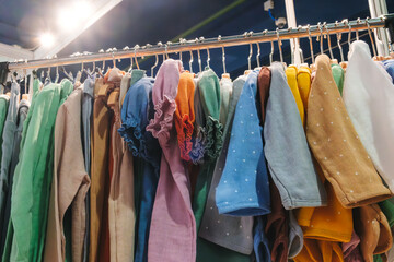 Poster - A rack of clothes with a variety of colors and patterns. The clothes are hanging on a rack, and the colors include green, yellow, blue, and brown