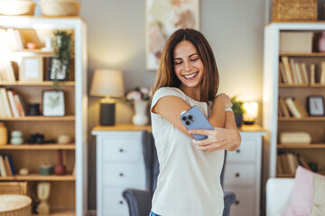 Wall Mural - Smiling Woman Taking a Selfie in Cozy Home Living Room Setting