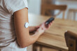 © Dragana Gordic - Person Using Glucose Monitor Patch While Holding a Smartphone