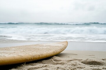 Wall Mural - surfboard rests on sandy shore, waves gently lapping at its edge